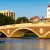 a bridge over a body of a water with some one in a kayak